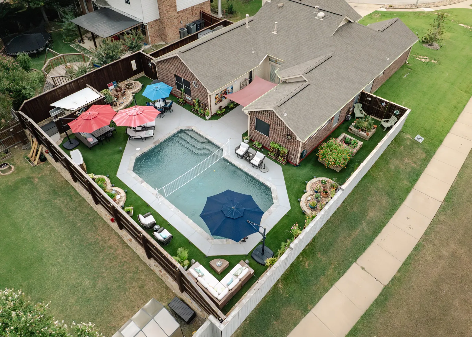 Aerial view of a landscaped backyard with swimming pool, patio seating, and garden beds by Greenview Landscaping in Fort Worth