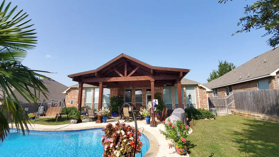 Covered outdoor living pavilion beside a backyard pool in Fort Worth